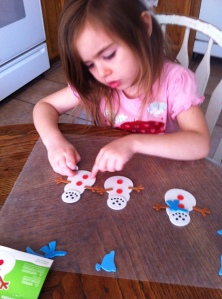 Olivia concentrating on getting her snowman's buttons "just so".